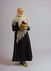 woman in a knitted shawl holds a basket of apples on a white background