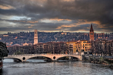 Puente sobre el río Adige en Verona en el atardecer con la ciudad al fondo,  bajo un cielo oscuro invernal.