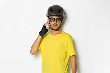 young handsome man wearing cyclist helmet using mobile phone isolated on white background

