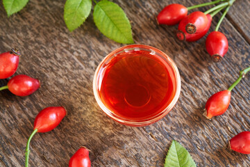 A bowl of rosehip seed oil with fresh rose hips