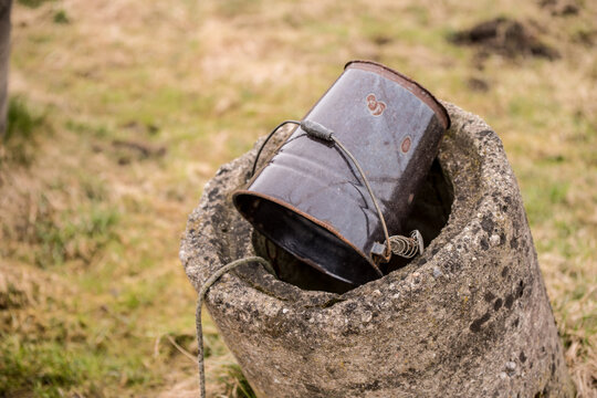 Old well with iron bucket on longrope for clean drinking water. Spring water at aluminum bucket from old well