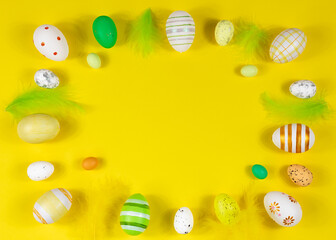 Easter frame with eggs and feathers on a yellow background. Minimal concept. View from above. Card with copy space for text.