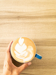 Hand holding cup of latte art coffee homemade on wooden background. copy space for your text
