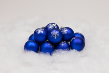 Collection of blue holiday ornaments with glittered snowflakes on front displayed on a snowy background