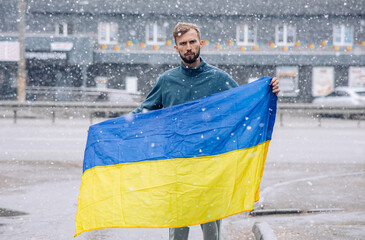 Angry man holds ukrainian flag in his hands and protests against Russia attack to Ukraine.