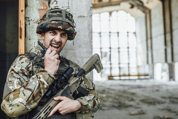 Fototapeta premium The military speaks rationally and holds a big rifle.