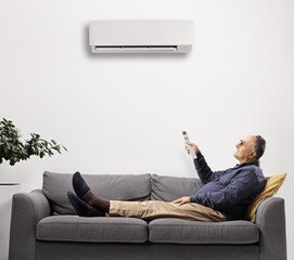 Mature man on a sofa putting the air conditioning on