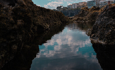 reflections in the water of the lava cliff
