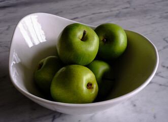 Colorful green plastic apples used for decorating and lifestyle on a marble table