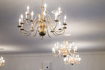 Several candelier lights hanging from a white ceiling to illuminate a room