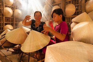 old vietnamese woman making a traditional conical hat at her home