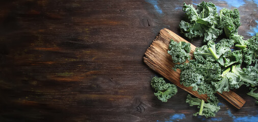 Fresh sliced Italian Kale salad on old wooden board. Dark background. Top view.