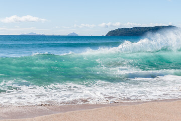 Surf waves crashing in on deserted beach at Tairua