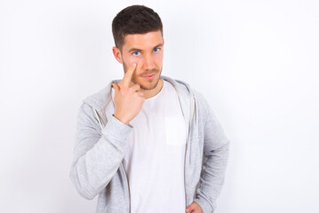 young caucasian man wearing casual clothes over white background, looking, observing, keeping an eye on an object in front, or watching out for something.