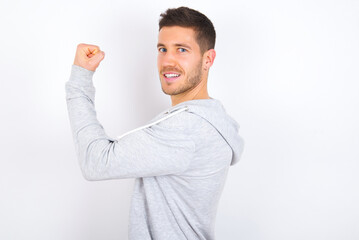 young caucasian man wearing casual clothes over white background,  showing muscles after workout....