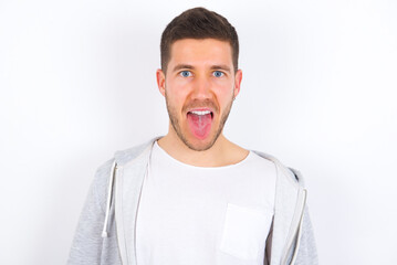 young caucasian man wearing casual clothes over white background with happy and funny face smiling and showing tongue.