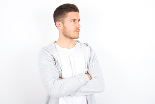 Image of upset young caucasian man wearing casual clothes over white background  with arms crossed. Looking with disappointed expression aside after listening to bad news.