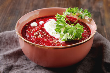 Traditional beetroot soup in a pink plate with Temyan, sour cream. Dark wood background. free space text.