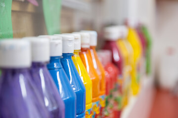 side view with shallow depth of field of row of colored finger paint cans at school