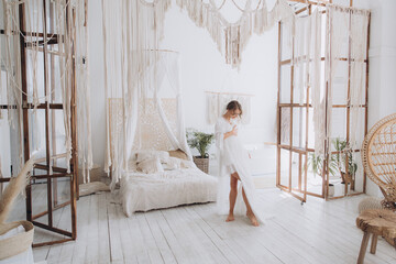 Morning of the bride in a rustic style, in a white bathrobe and a white bouquet on the bed and in...
