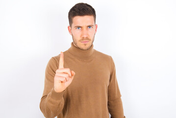 young caucasian man wearing knitted turtleneck over white background frustrated and pointing to the front