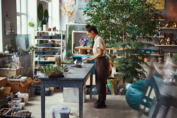 Concentrated florist adding the potting mix to a geometric florarium