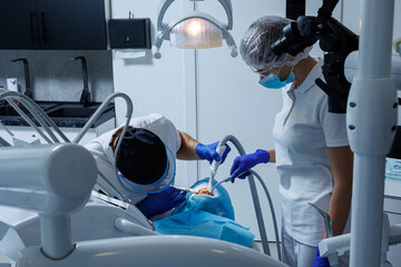A professional dentist examines a patient's teeth with dental equipment and holds dental...