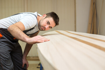 Obraz premium Young carpenter making wooden canoe in his workshop
