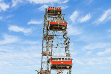 Fototapeta premium Ferris wheel with red cabins of the Prater amusement park in Vienna, Austria. Historical monument