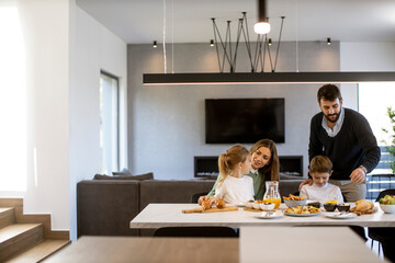 Young happy family talking while having breakfast at dining table