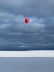 Fototapeta premium Mongolfiera rossa vola nel cielo blu d’inverno