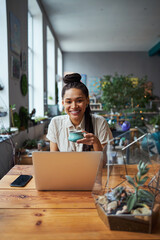 Joyful good-looking florist seated at a wooden table