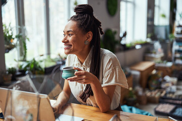 Happy lovely female florist daydreaming in the workplace