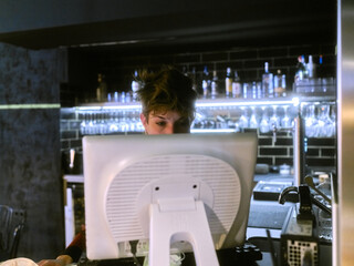 Restaurant manager working at the reception desk using a computer