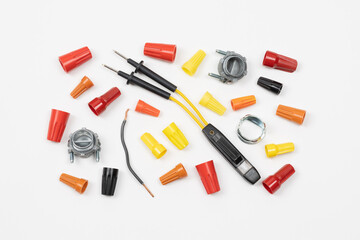 Horizontal flat layout of assorted color wire nuts, connectors, electricity tester, and wire on...