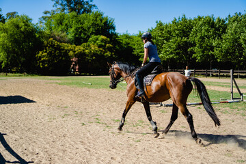 young latin woman practicing horseback riding in the countryside, freeze moment, daytime