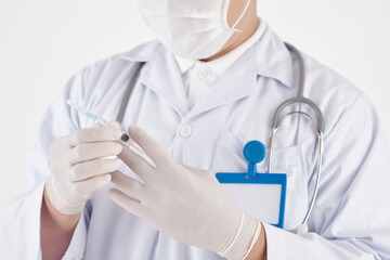 Hands of doctor in rubber gloves holding syringe with vaccine against coronavirus