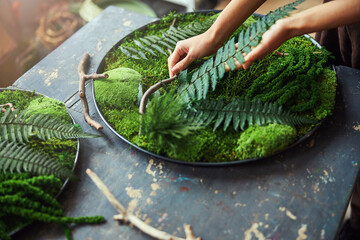 Professional florist working on a circle moss art piece - obrazy, fototapety, plakaty