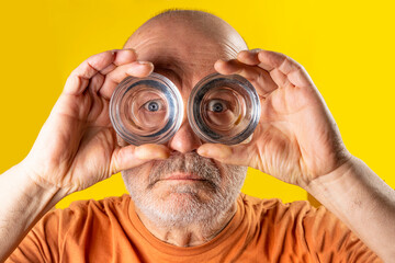 A man looking through the bottoms of glasses like binoculars	