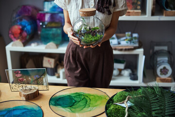 Female florist with a florarium standing at a table