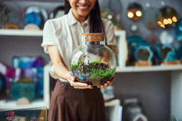 Smiling floral designer showing her florarium with a cork lid