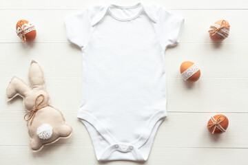 Easter mockup of white baby bodysuit on wood background with decorated eggs and beige linen easter...