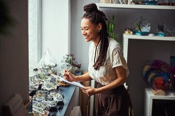 Pleased florist examining plant terrariums on the windowsill
