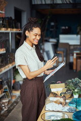 Pleased floral decorator reading a text message on her cellphone