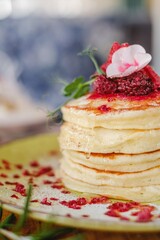 delicious pancakes with syrup in a stack and flower decoration on top a wooden table.