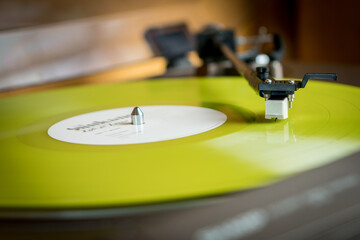 Obraz premium Closeup view of a tonearm and turntable playing color yellow vinyl record.