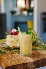 fruit Fresh drink with delicious pancakes with syrup in a stack and flower decoration on top a wooden table.