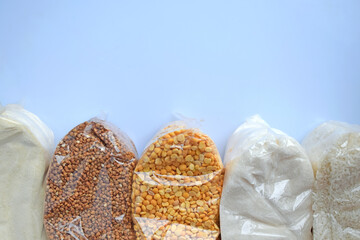 A set of plastic transparent bags with cereals on a blue background. Donations.