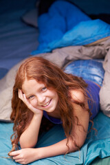 She loves camping. Portrait of a happy young girl lying in her tent while camping.