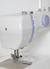 White modern sewing machine on a table. Tailor's workplace,